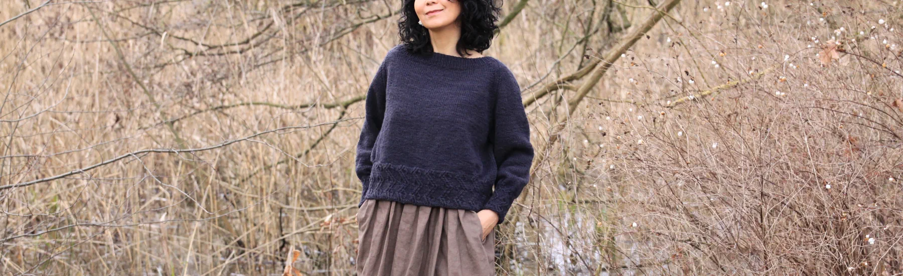 Chihiro is weareing lattice sweater with grass in the background